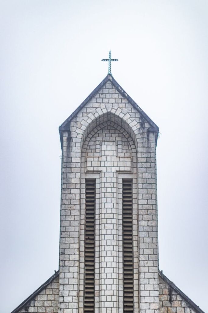 Close-up of a historic church tower showcasing classic stone architecture and cross.